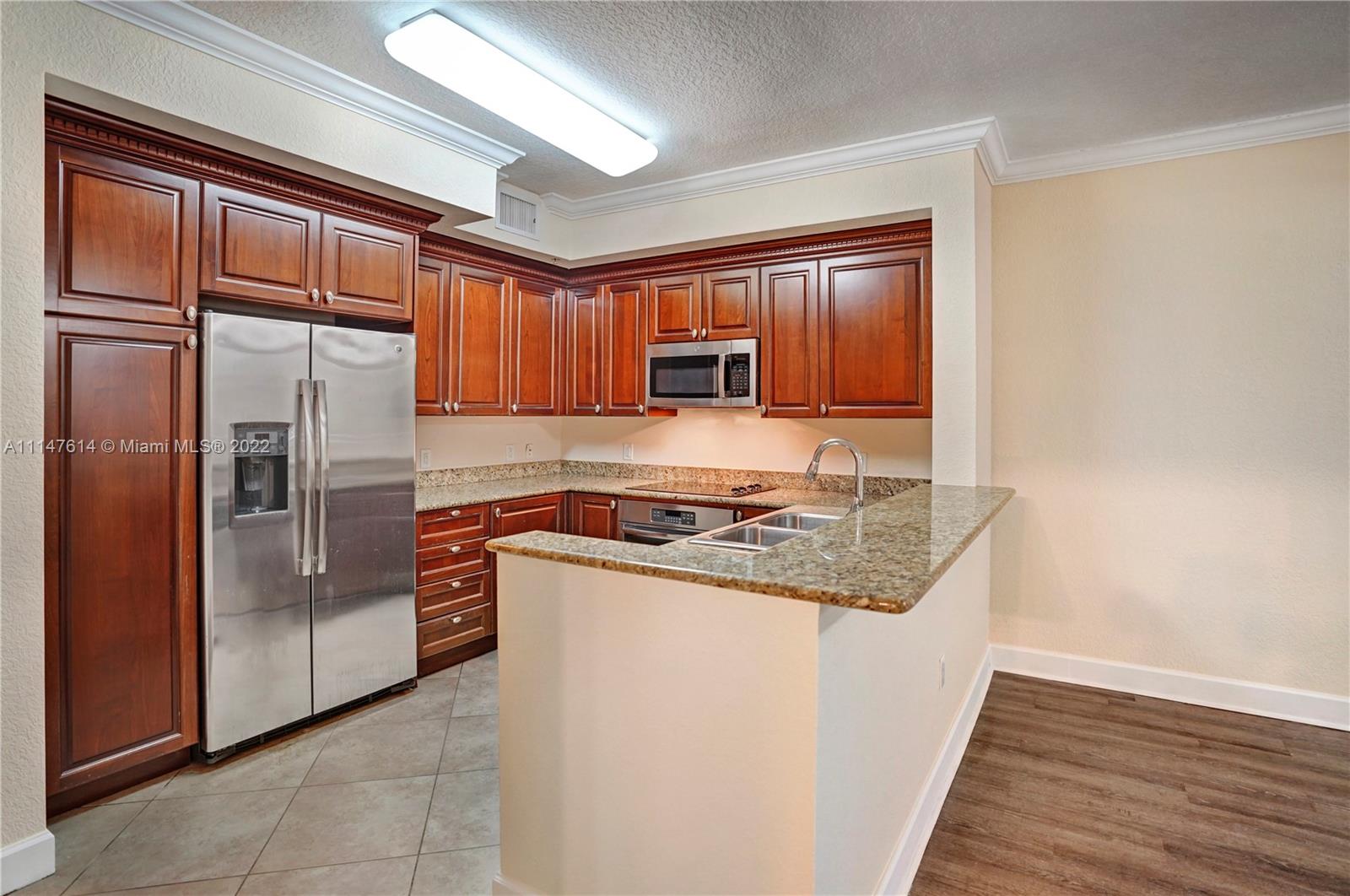 1660 Renaissance Commons Boulevard, Unit 2203 Boynton Beach, FL 33426 - Photo 3 of 20 a kitchen with stainless steel appliances granite countertop a refrigerator a stove and a sink with wooden floors