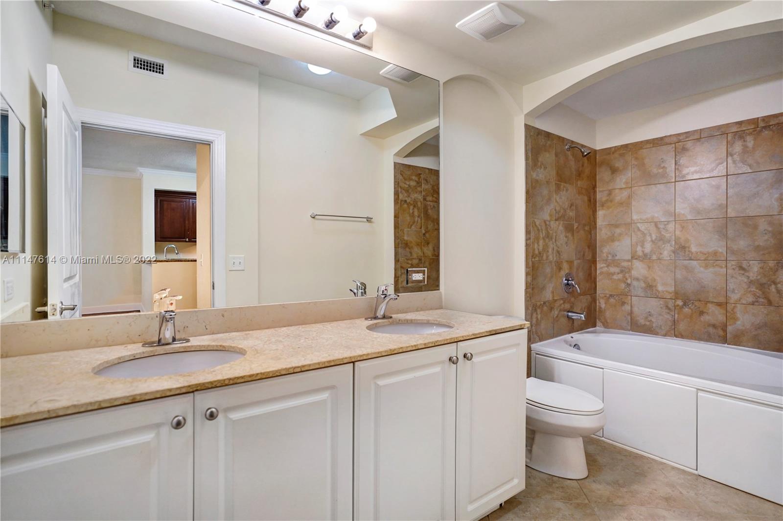 1660 Renaissance Commons Boulevard, Unit 2203 Boynton Beach, FL 33426 - Photo 5 of 20 a bathroom with a granite countertop sink a toilet a mirror and bathtub
