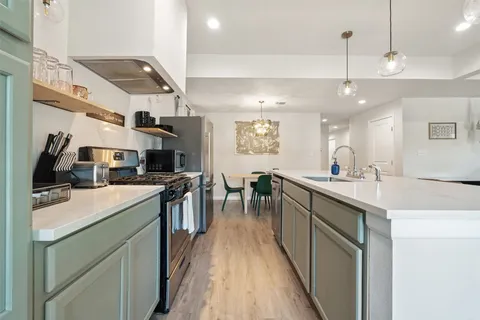 a kitchen with stainless steel appliances granite countertop a sink a stove and a refrigerator