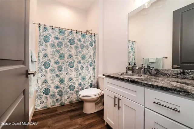 a bathroom with a granite countertop toilet a sink and a mirror