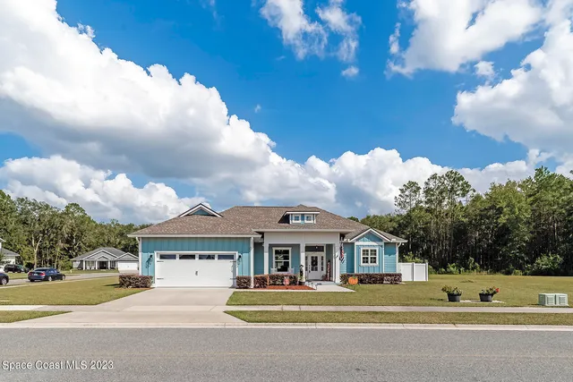 a view of a white house with a big yard and large trees