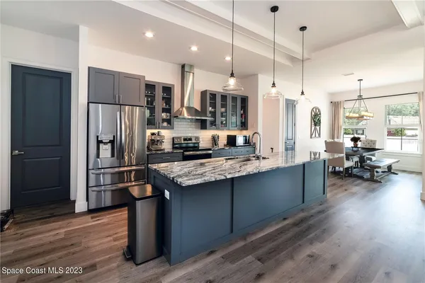 a kitchen with stainless steel appliances granite countertop a refrigerator a stove and a wooden floors