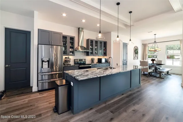 a kitchen with stainless steel appliances granite countertop a refrigerator a stove and a wooden floors