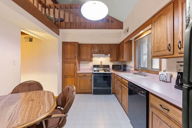 a kitchen with stainless steel appliances granite countertop a sink a stove a refrigerator cabinets wooden floor and a window