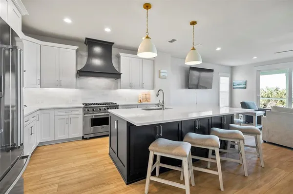 a kitchen with stainless steel appliances a stove a sink a oven a dining table and chairs