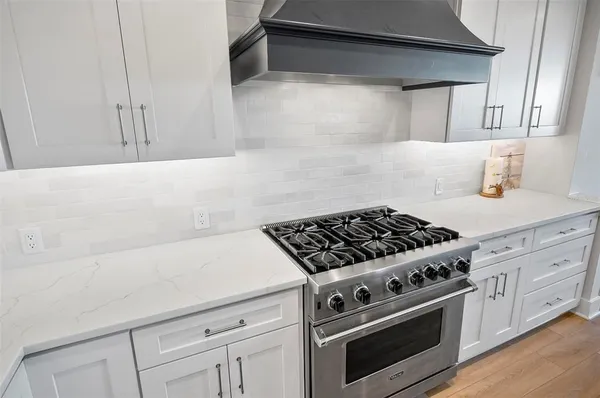 a kitchen with stainless steel appliances granite countertop a sink a stove and a wooden floors