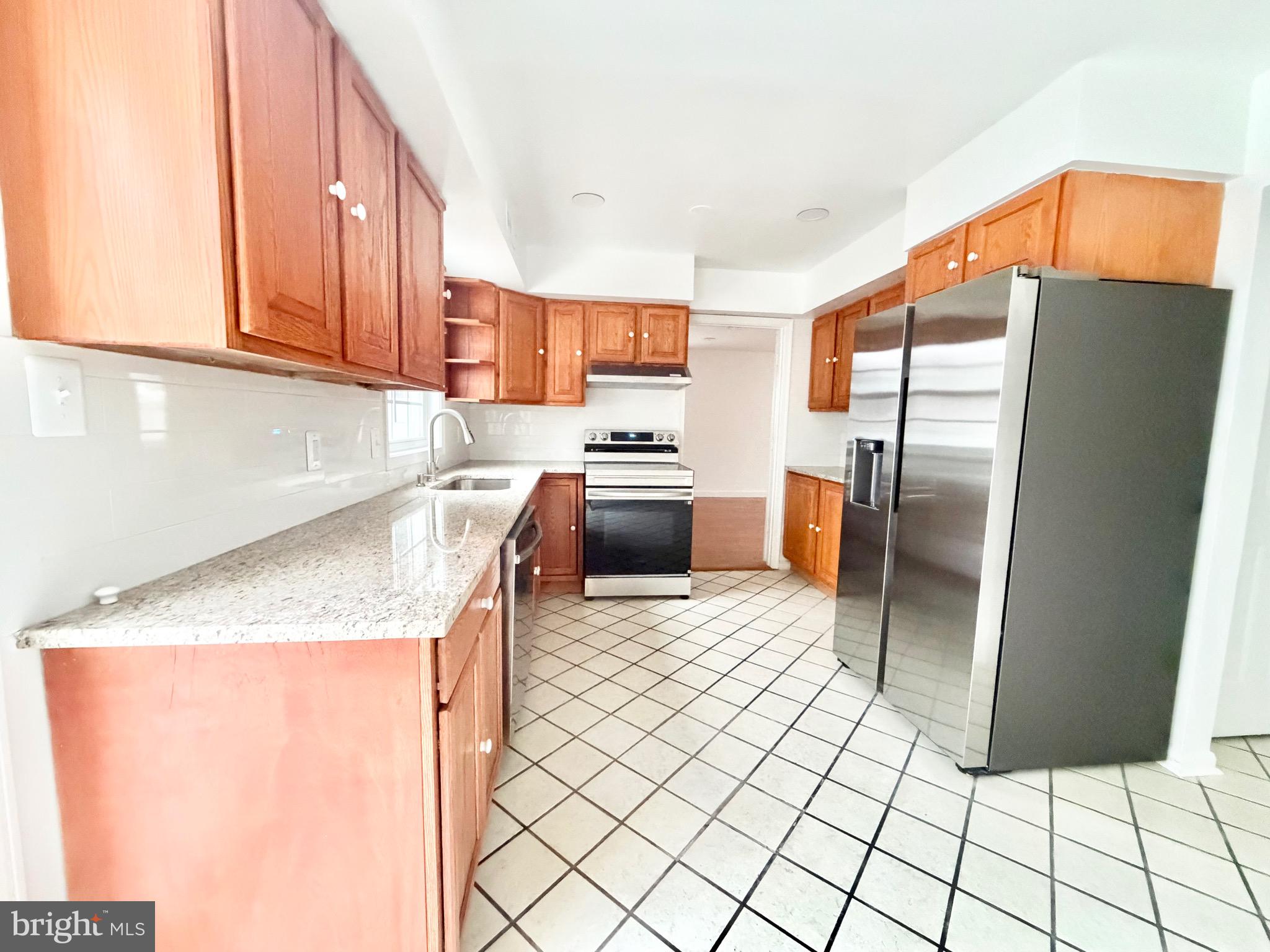 4001 Middle Ridge Drive Fairfax, VA 22033 - Photo 2 of 17 a kitchen with stainless steel appliances granite countertop a refrigerator a stove and a sink with wooden cabinets