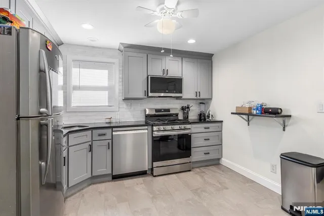 a kitchen with stainless steel appliances granite countertop a stove top oven a sink and a refrigerator