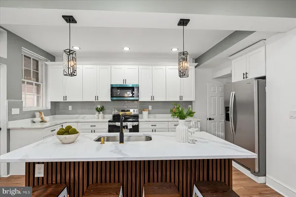a kitchen with kitchen island a counter appliances a sink and cabinets