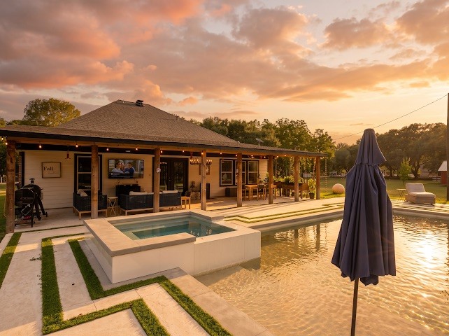 1114 Wagon Road Simonton, TX 77485 - Photo 6 of 48 Experience luxurious outdoor living with a stylish patio, sparkling pool, and inviting spa, perfect for entertaining and relaxation under the stunning sunset.