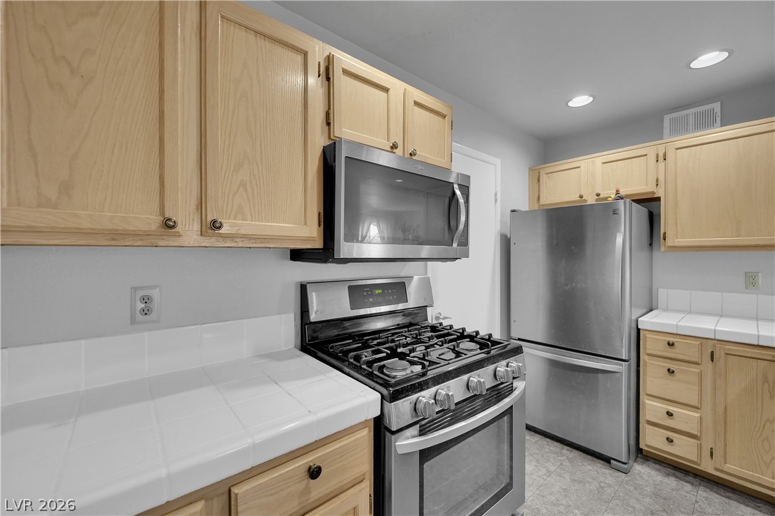 7570 West Flamingo Road, Unit 115 Las Vegas, NV 89147 - Photo 9 of 34 A well-equipped kitchen features a stainless steel appliance suite with wood cabinetry and practical tile counters.