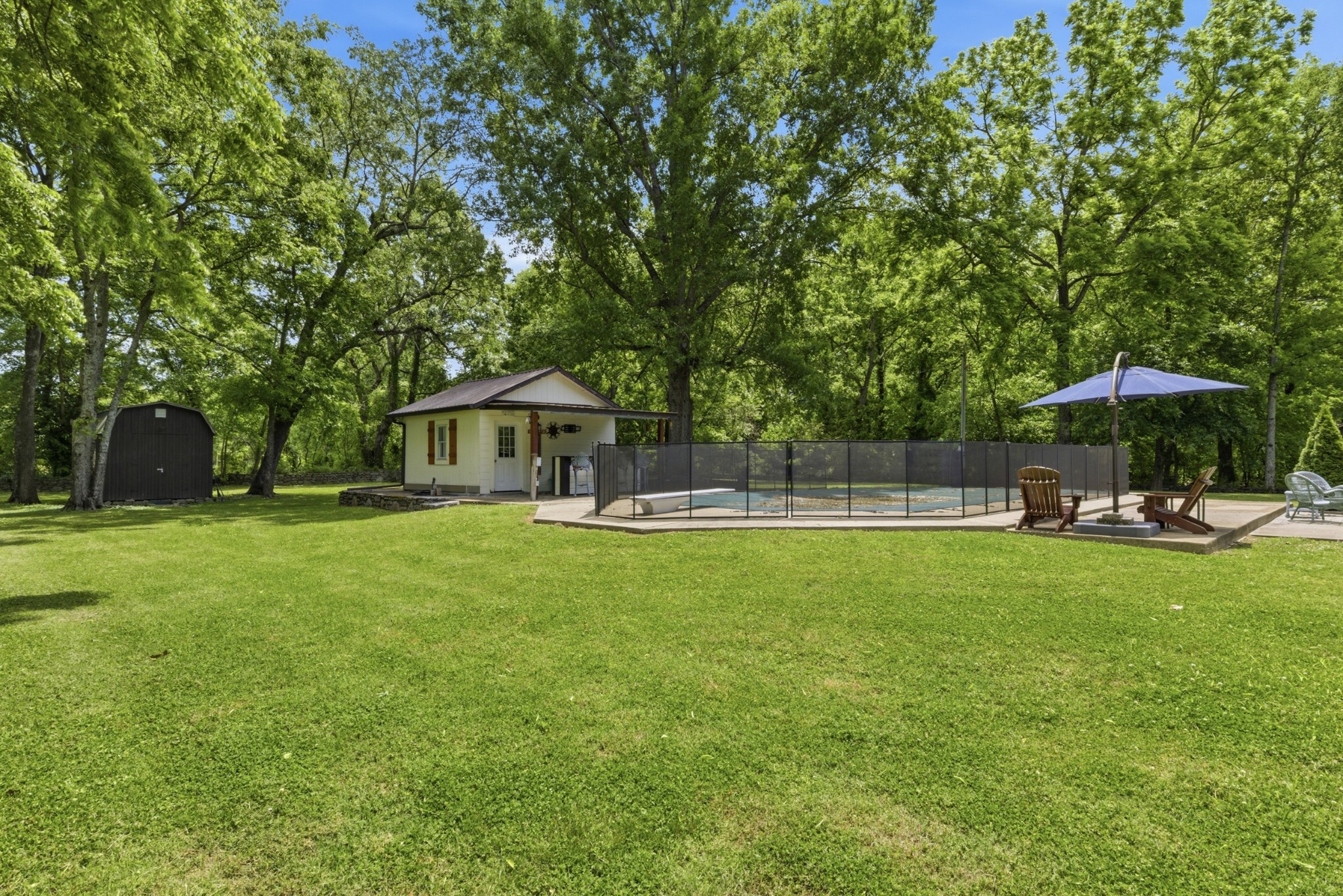 2540 Carl Fox Road Cornersville, TN 37047 - Photo 41 of 48 a view of a swimming pool with a table and chairs under an umbrella