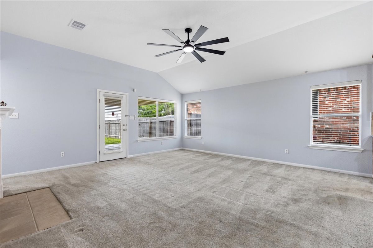 17812 Masi Loop Pflugerville, TX 78660 - Photo 17 of 38 Spacious interior room featuring a vaulted ceiling with a modern ceiling fan, gray carpeting, light-toned walls, and multiple windows
