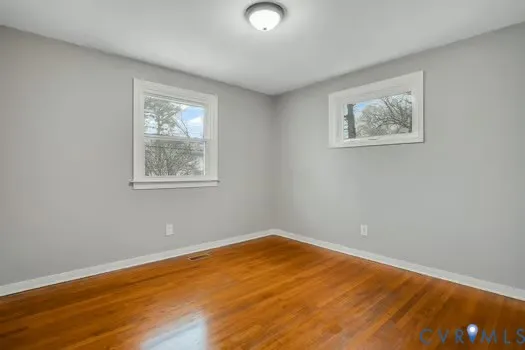 a view of empty room with wooden floor and window