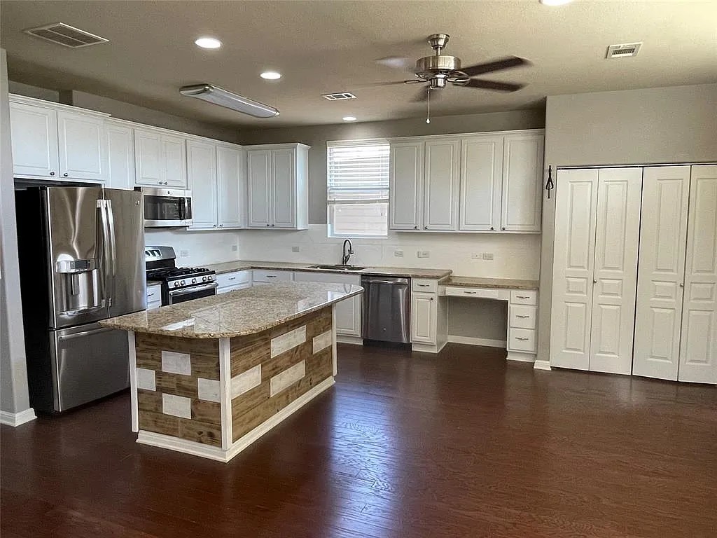 5136 Hellman Kyle, TX 78640 - Photo 5 of 17 Kitchen with appliances with stainless steel finishes, white cabinets, ceiling fan, light stone countertops, and a kitchen island