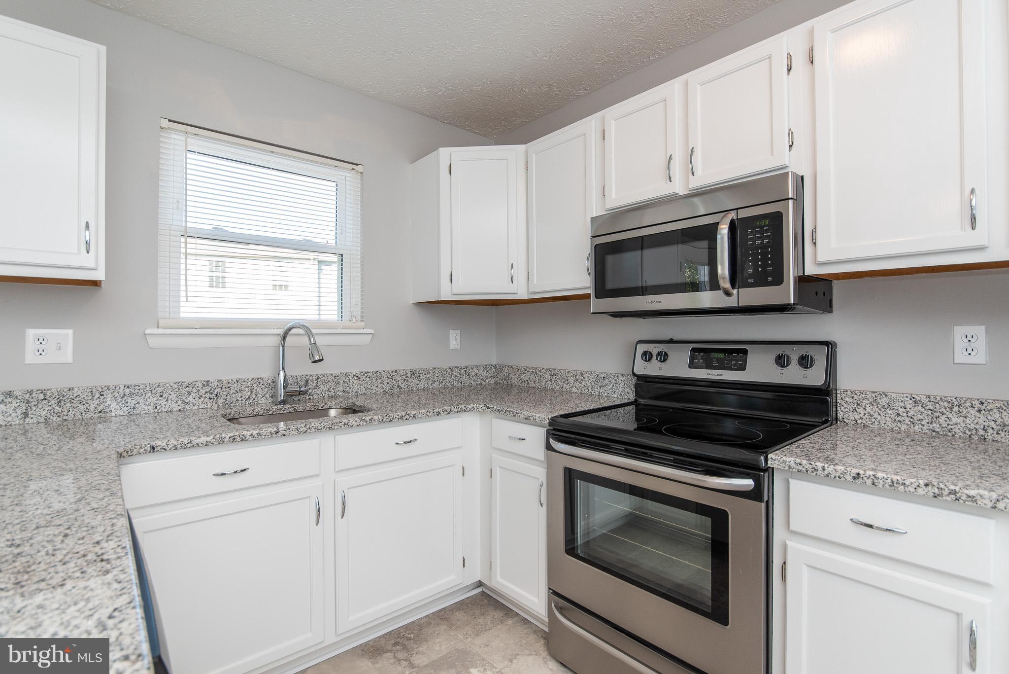 426 Kosoak Road Baltimore, MD 21220 - Photo 9 of 30 a kitchen with granite countertop white cabinets appliances a sink and a window