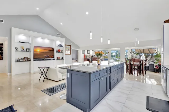 a kitchen with stainless steel appliances kitchen island granite countertop a table chairs and a refrigerator