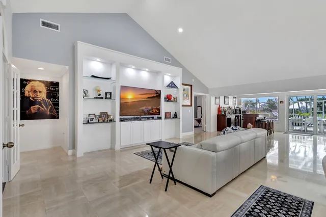 a view of a dining room and livingroom with furniture a potted plant and windows