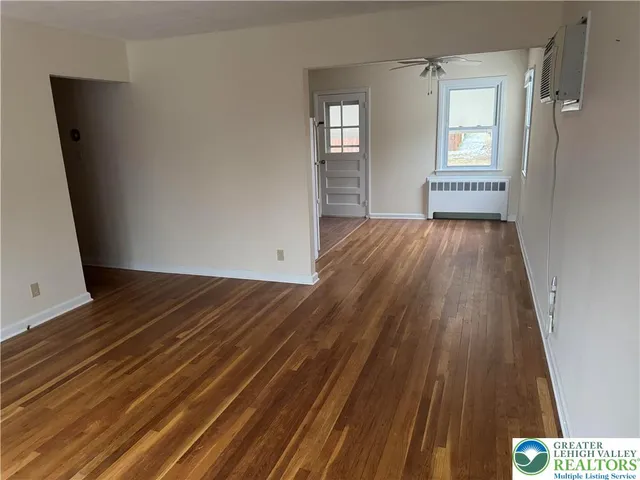 a view of an empty room with wooden floor and a window