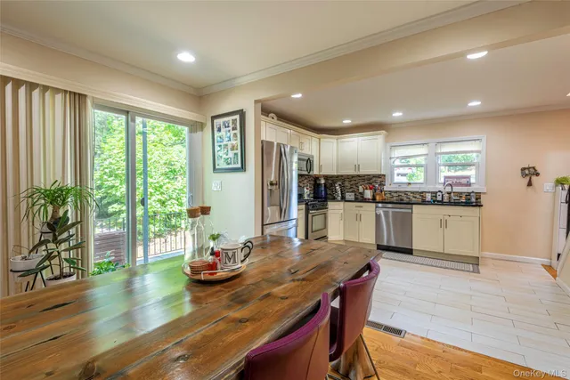 a kitchen with stainless steel appliances granite countertop a stove a refrigerator a sink a dining table and chairs