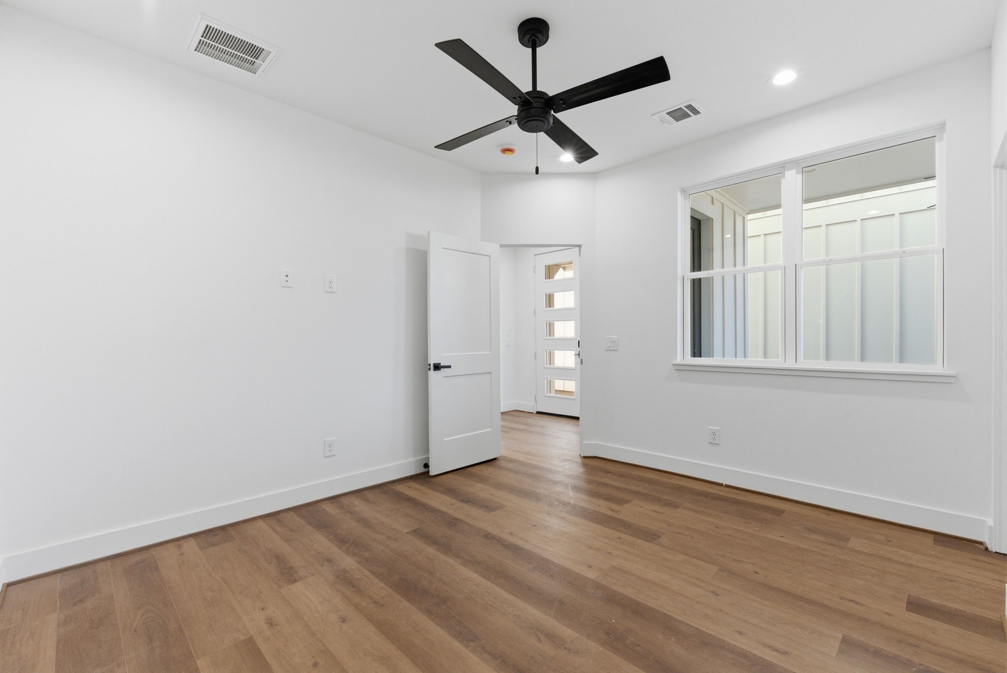 7706 Earl Rudder Way Houston, TX 77055 - Photo 11 of 46 an empty room with wooden floor ceiling fan and windows