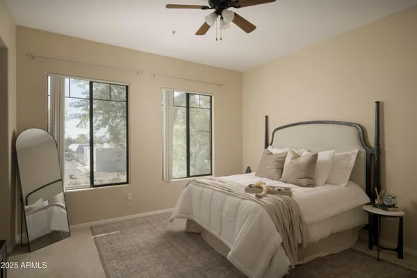 a bedroom with a bed a mirror and windows