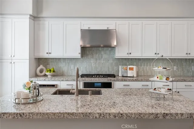 a kitchen with a stove a sink and a white cabinets