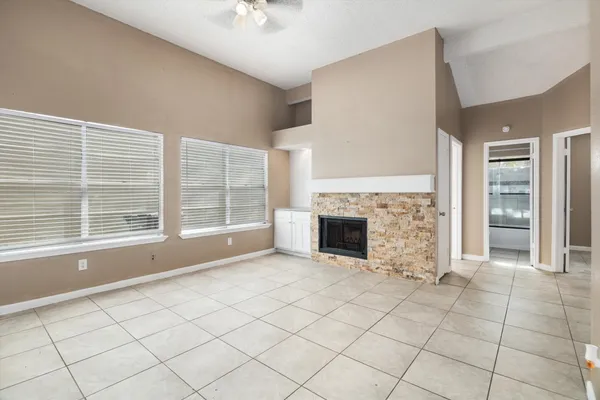 an empty room with windows and fireplace