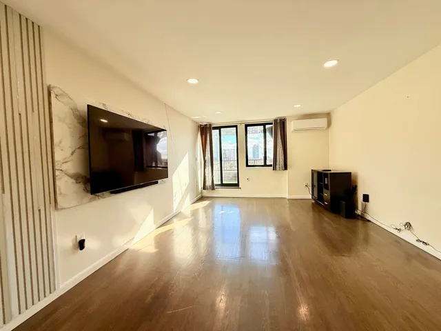 a view of a livingroom with wooden floor and a flat screen tv