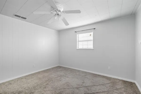 an empty room with a window and a fan