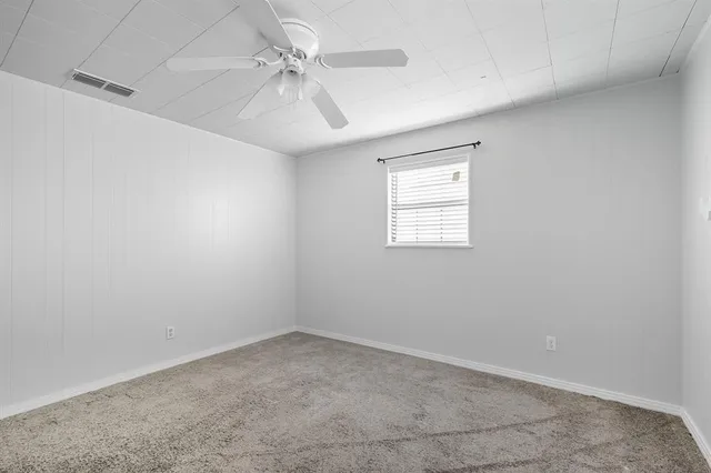 an empty room with a window and a fan