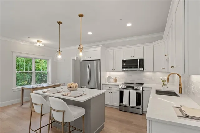 a kitchen with stainless steel appliances granite countertop a stove a sink a microwave a refrigerator with a dining table and chairs