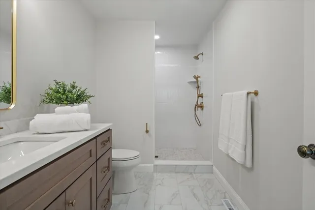 a bathroom with a granite countertop sink a toilet and shower