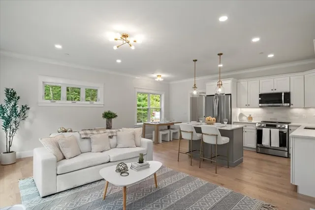a living room with furniture kitchen area and a wooden floor