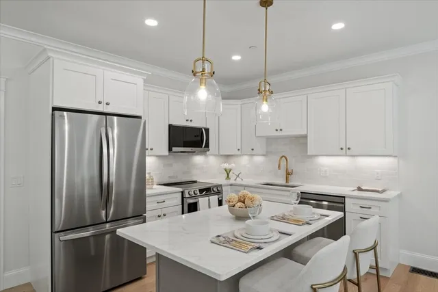 a kitchen with stainless steel appliances granite countertop a refrigerator a sink a stove a dining table and chairs