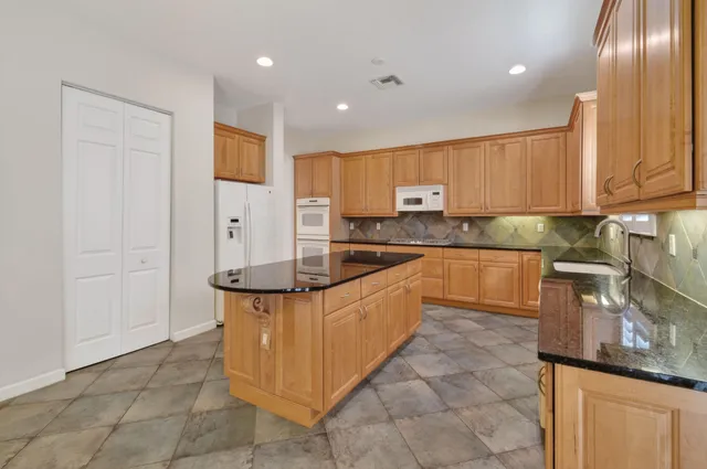 a large kitchen with stainless steel appliances granite countertop a stove and a sink
