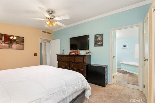a bedroom with a bed and a flat tv screen on dresser