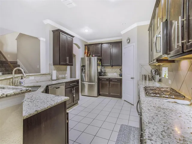 a kitchen with stainless steel appliances kitchen island granite countertop a sink stove and refrigerator