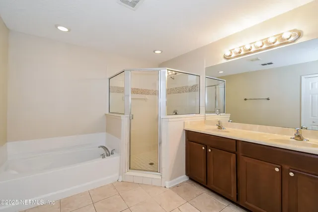 a bathroom with a bathtub a double vanity sink and mirror