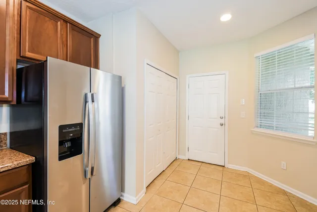 a view of a refrigerator in kitchen and an empty room in wooden floor