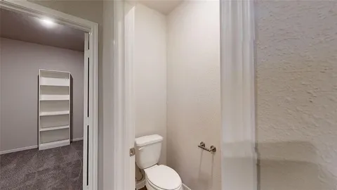 a white toilet sitting in a bathroom next to a window