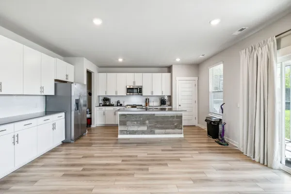 a large kitchen with stainless steel appliances granite countertop a refrigerator and cabinets