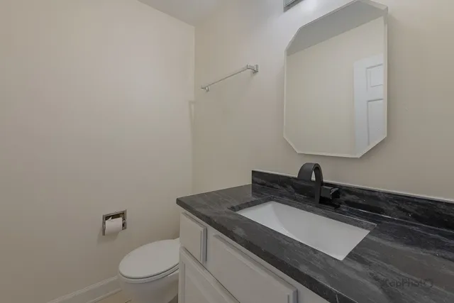 a bathroom with a granite countertop sink a toilet and mirror