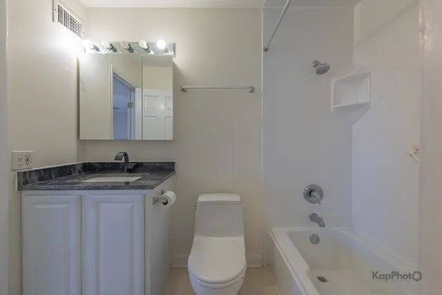 a bathroom with a granite countertop sink a toilet and bathtub