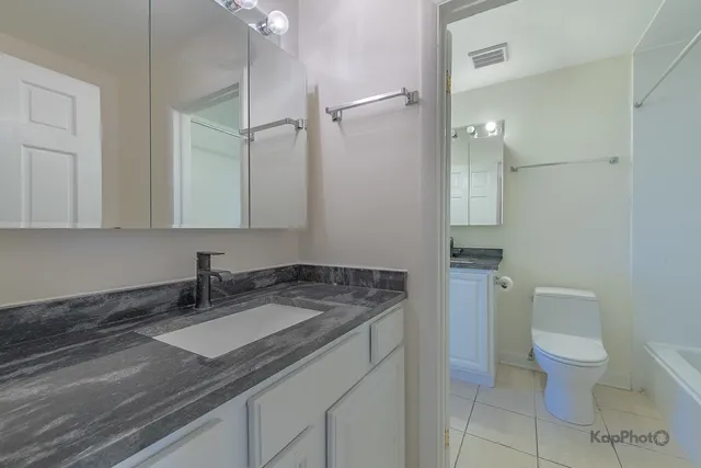 a bathroom with a granite countertop sink a toilet and a mirror