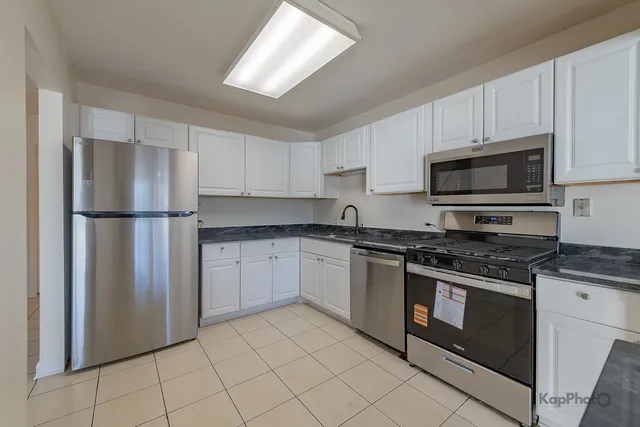 a kitchen with stainless steel appliances granite countertop a stove a refrigerator and a microwave