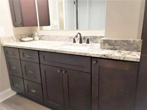 a bathroom with a granite countertop sink and a mirror