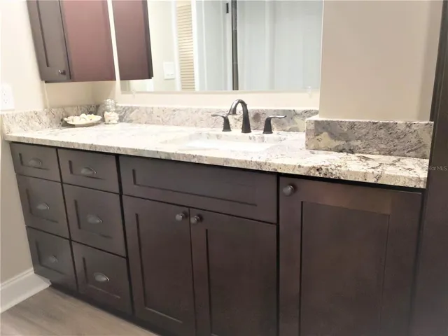 a bathroom with a granite countertop sink and a mirror