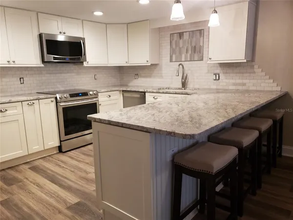 a kitchen with stainless steel appliances granite countertop a kitchen island hardwood floor sink and stove