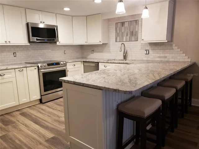 a kitchen with stainless steel appliances granite countertop a kitchen island hardwood floor sink and stove